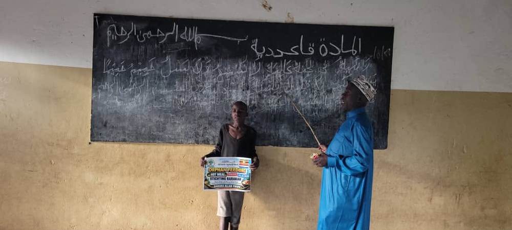 Een leraar geeft Arabische les aan een kind in Naboa, Uganda